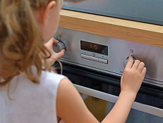 A child using the knobs on an oven
